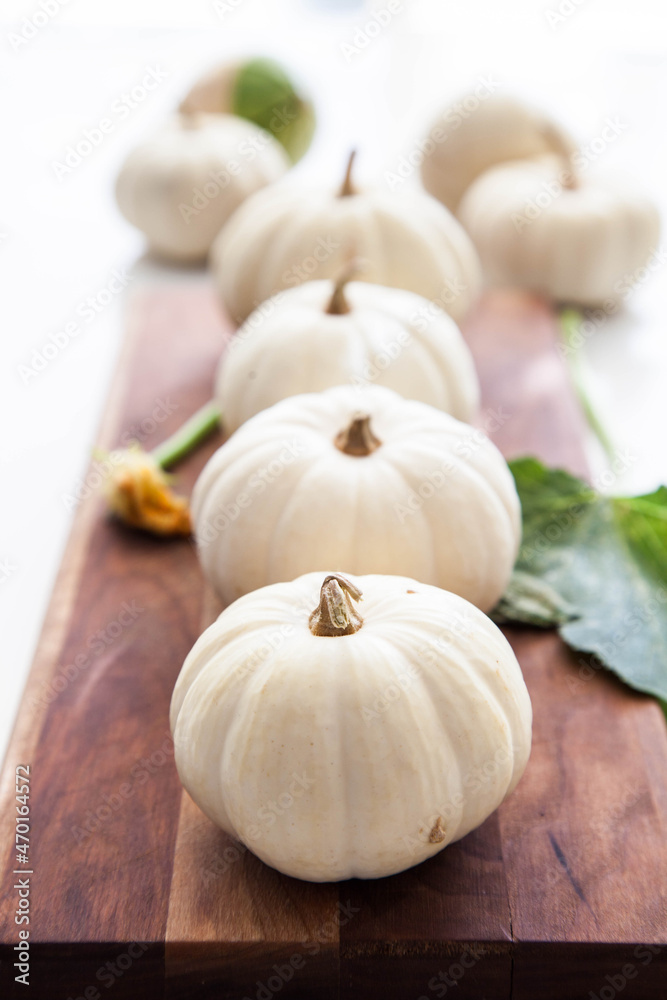 White mini pumpkins on wooden board