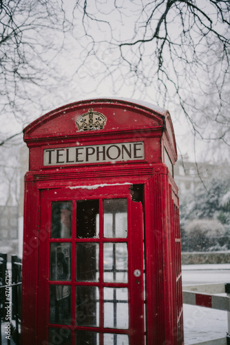 A red telephone booth in London under the snow