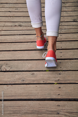 Woman in red shoes and white jeans on wooden boards.