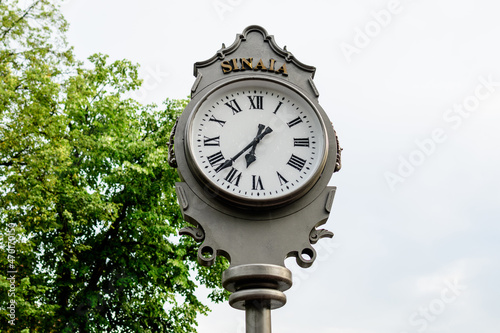 Vintage style grey metallic clock towards cloudy sky in Sinaia Park, Romania, in a rainy summer day.