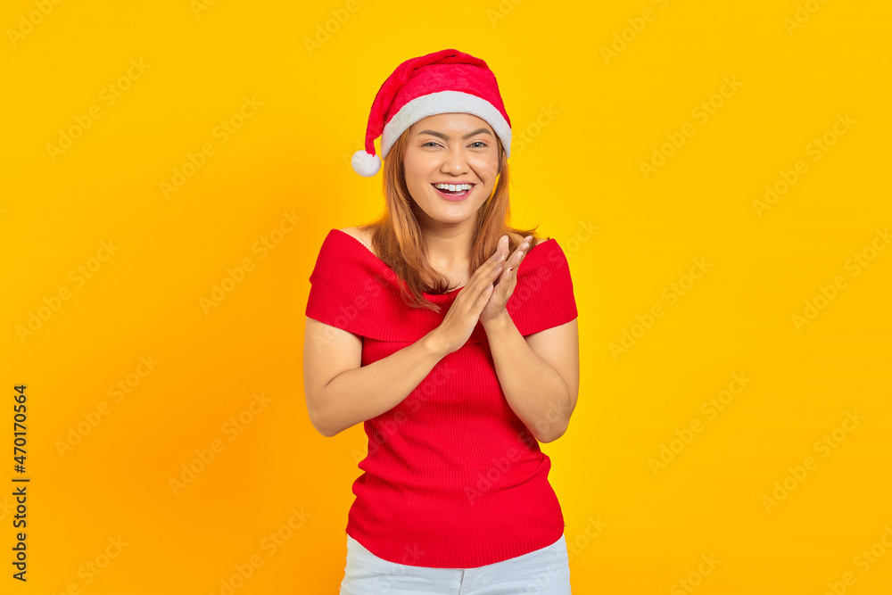 Smiling young woman wearing Christmas hat and applauding after presentation in a conference on yellow background Smiling young woman wearing Christmas hat and applauding after presentation in a conference on yellow background
