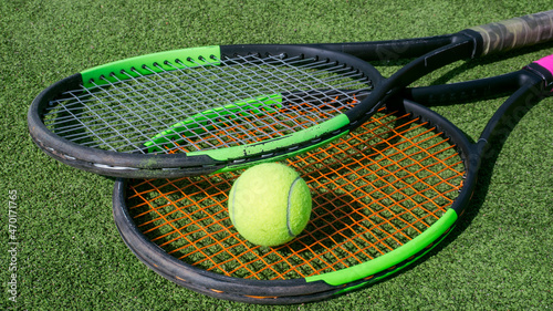tennis ball and racket lie on the green court close up. © Vitali