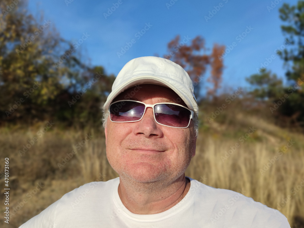 portrait of a smiling man in sunglasses and a cap in nature portrait of a smiling man in sunglasses and a cap in nature