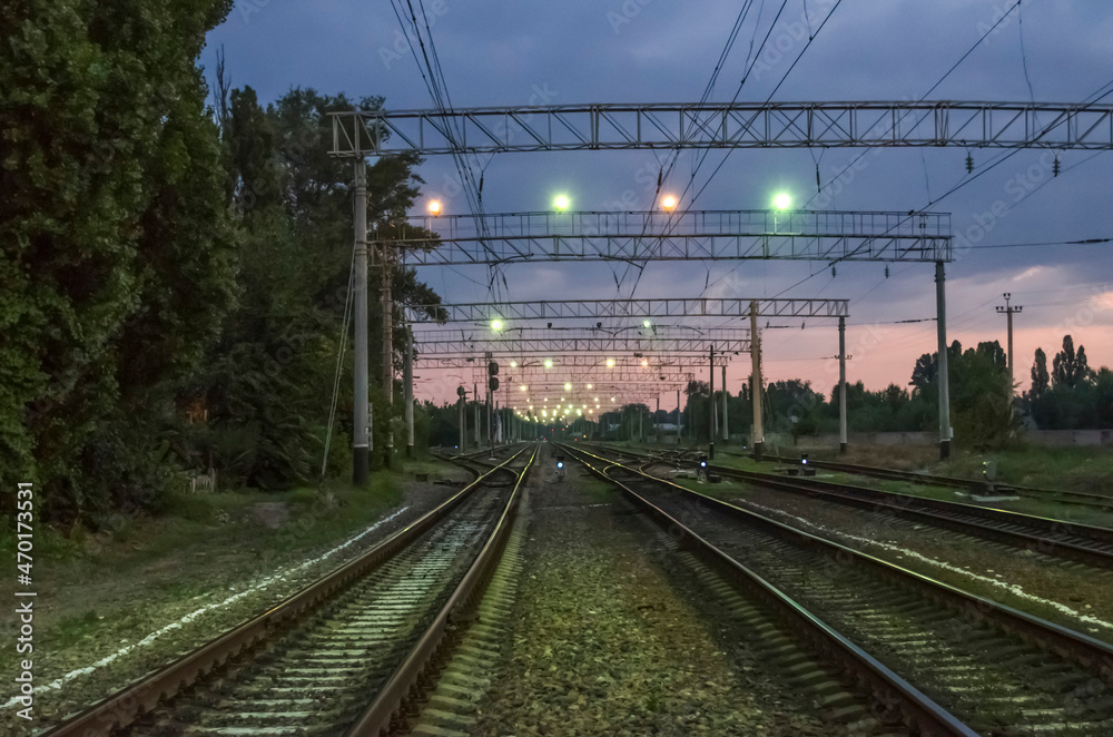 A railway illuminated by multicolored lights at dawn