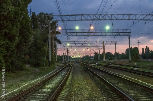 A railway illuminated by multicolored lights at dawn