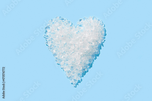 Crushed ice in heart shape on blue background. Summer refreshment concept