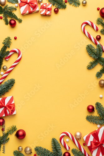 Yellow Christmas background with frame of fir decorations and ornaments
