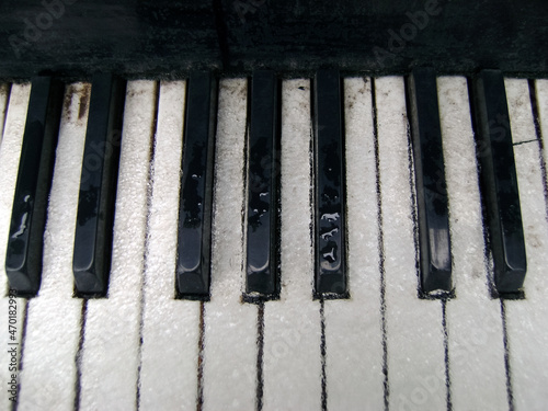 Outdoor grand piano on open air. Closeup. Ice, snow and water on the piano keys. The balance of notes is the key to an adequate melody.