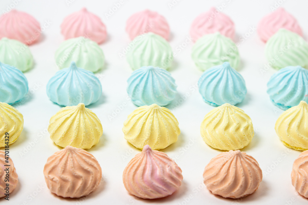 Multicolored meringues on a white background. Light and tasty dessert. Multicolored meringues on a white background. Light and tasty dessert.