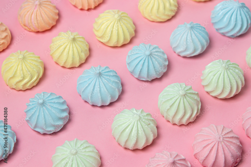 Multicolored meringues on a pink background. Meringue of different colors folded in several rows by color Multicolored meringues on a pink background. Meringue of different colors folded in several rows by color