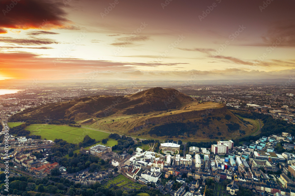 Aerial sunrise view of Holyrood Park is the largest of Edinburgh's royal parks, climb to Arthur's Seat for stunning views of the city, explore the castle where Scottish kings lived or visit museums