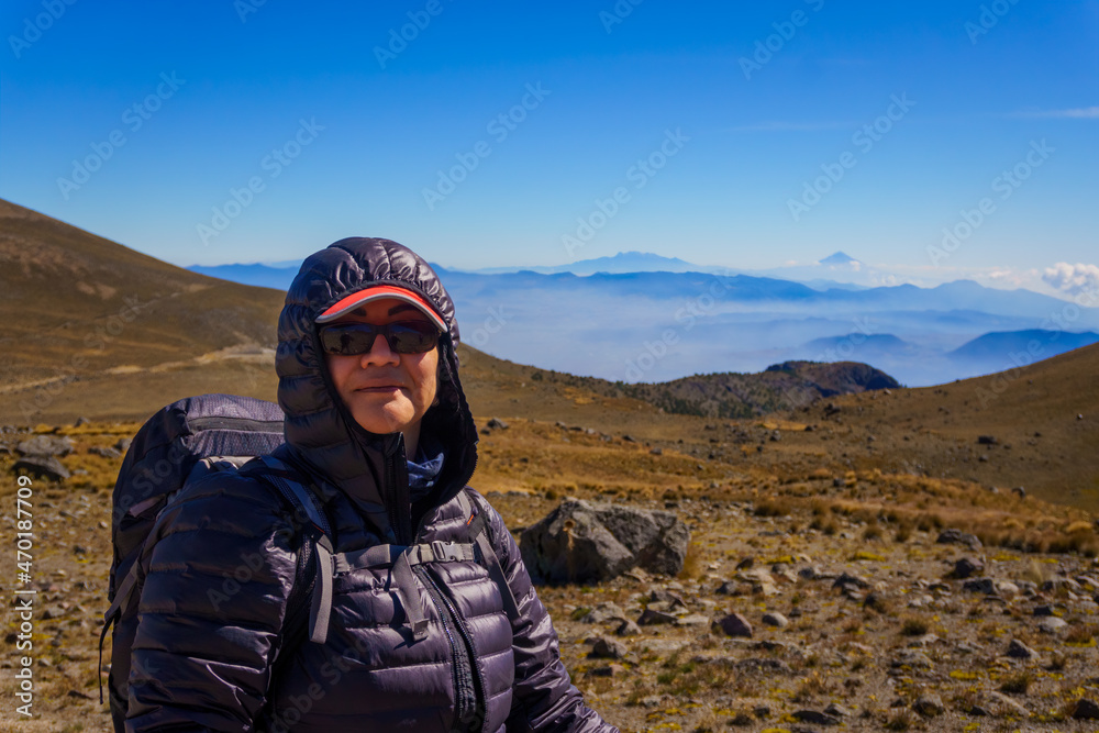 Portrait of a happy woman hiker standing on the slope of mountain