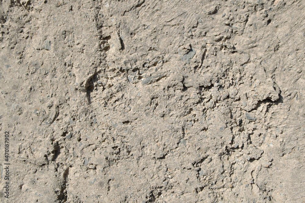 The rough, uneven surface of the cement wall is gray-brown. The rough, uneven surface of the cement wall is gray-brown.