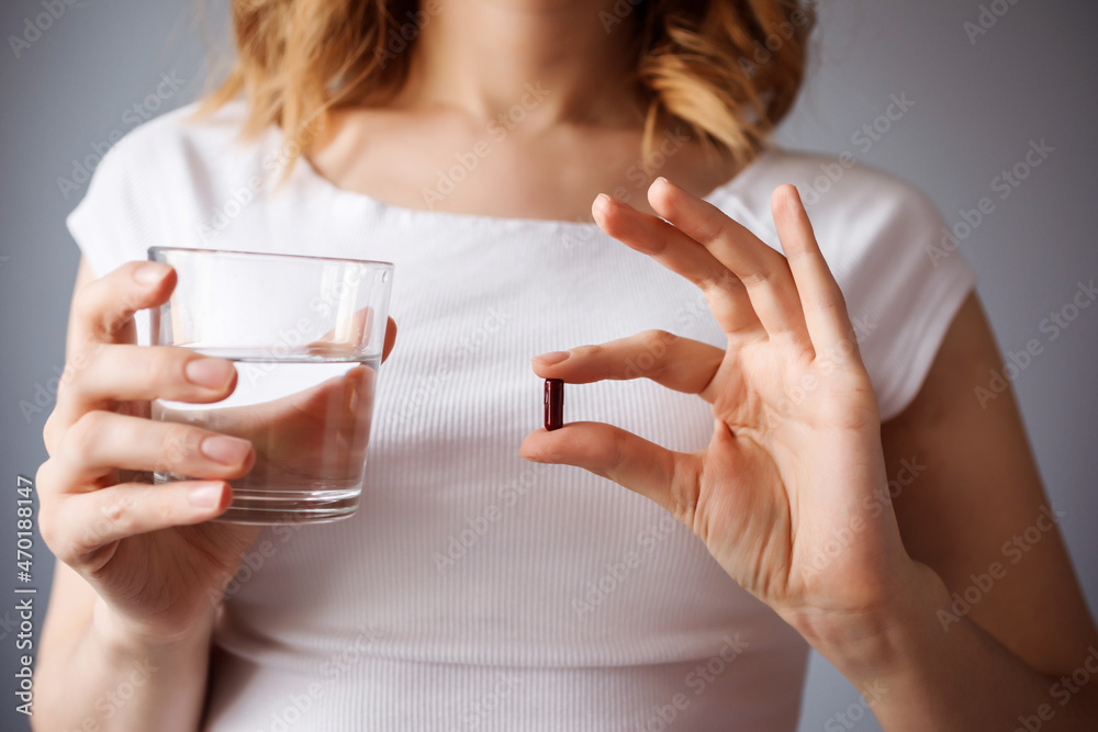 Close up view of woman holding pill and glass of water. Health care, treatment, medication in modern life. Close up view of woman holding pill and glass of water. Health care, treatment, medication in modern life.