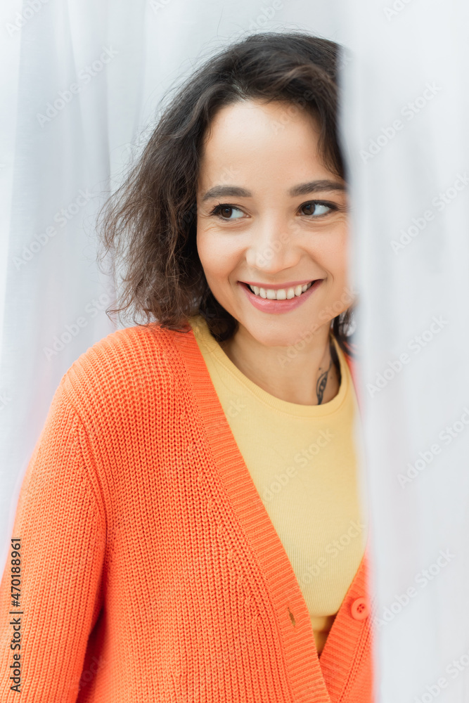 portrait of positive young woman with tattoo smiling near white curtain. portrait of positive young woman with tattoo smiling near white curtain.