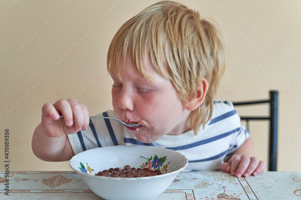 Little boy is having breakfast with chocolate balls with milk Little boy is having breakfast with chocolate balls with milk
