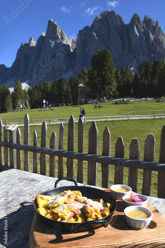 Der Kaiserschmarrn ist eine Mehlspeise. Sie  zählt zu den Süßspeisen der österreichischen Küche. Serviert wird hier mit Staubzucker, Apfelmus, Rosinen vor den Geislerspitzen in den Dolomiten Italien.