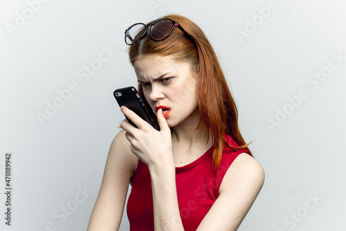 emotional red-haired woman with a phone in her hands communicating gadget