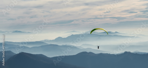 Paraglider flies in the sky over the mountains on a bright sunny day. Paragliding. Concepts: adventure, determination, extreme sports. Alpine ski resort. Rest in Ukraine, Carpathian.