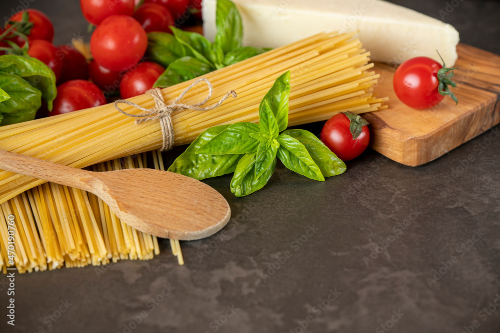 spaghetti on a dark background, cheese, tomatoes, and basil spaghetti on a dark background, cheese, tomatoes, and basil