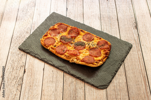 Pepperoni is an American variety of salami, made from cured pork and beef mixed and seasoned with paprika or other chili, characteristically mild, lightly smoked, and bright red in color. photo