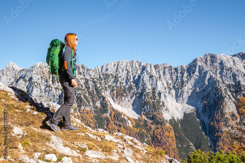 Woman walking in mountains with golden larch trees in autumn.