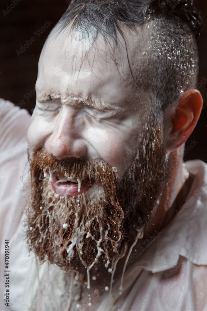 Portrait of a bearded man in streams of milk.