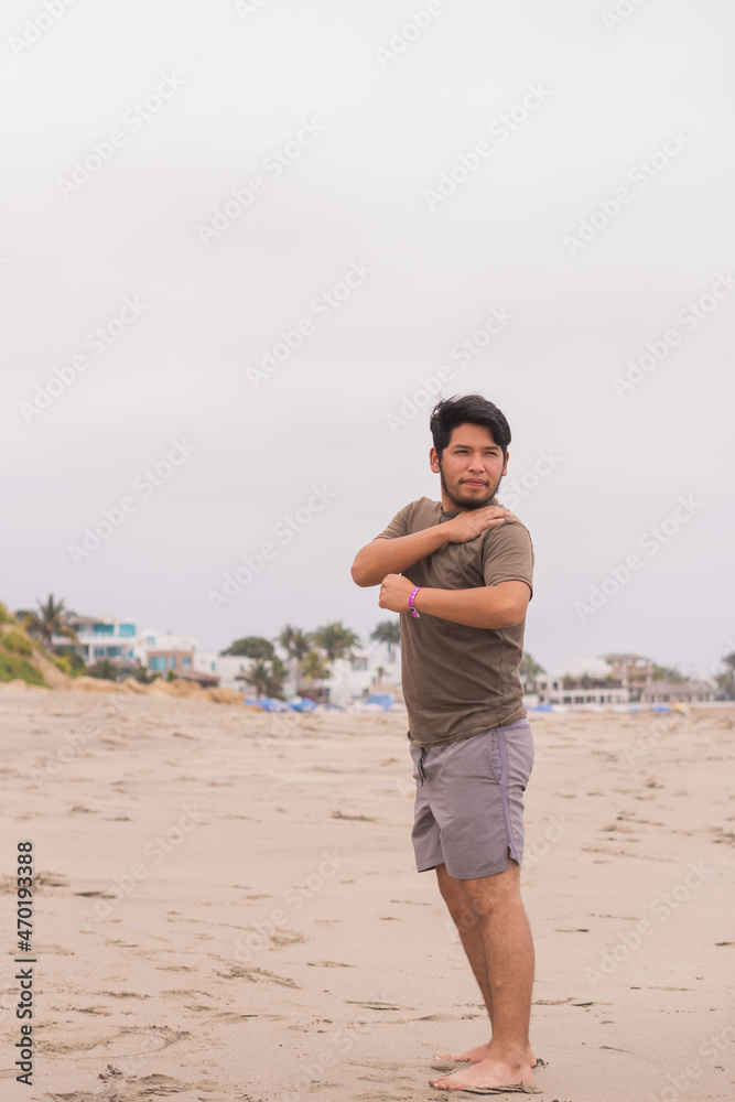 Young man practicing various poses in yoga on the beach.