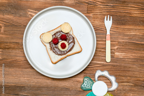 Funny bear face sandwich toast bread with peanut butter, cheese and raspberry on plate wooden background. Kids child sweet dessert breakfast lunch food