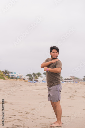 Young man practicing various poses in yoga on the beach.
