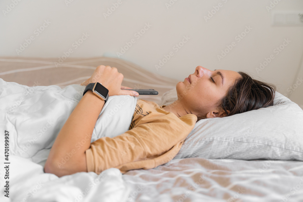 Young woman goes to sleep Phone addiction, insomnia. try to fall asleep. Sleep tracking on the phone and smart watch. Circadian rhythm. Young woman goes to sleep Phone addiction, insomnia. try to fall asleep. Sleep tracking on the phone and smart watch. Circadian rhythm.