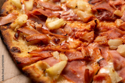 Ham and pineapple pizza called hawaiian on a wooden background