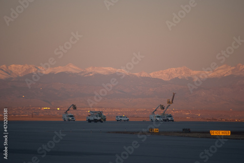 Airport machinery in front of Rocky Mountains landscape at sunrise in denver international airport