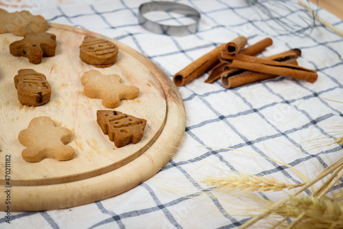 Homemade Christmas ginger bread cookies on wooden try with cinnamon, Xmas gingerbread cookie, preparing bakery, process of baking and cooking at home.