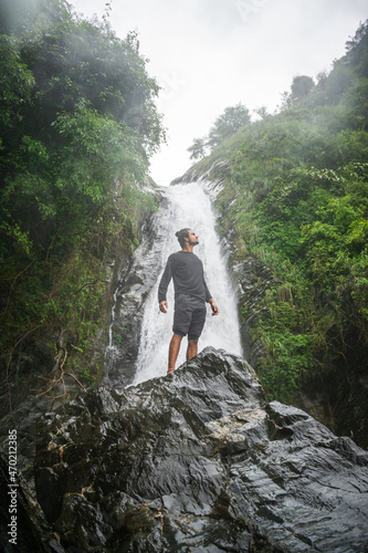 young boy standing in front of a waterfall photo