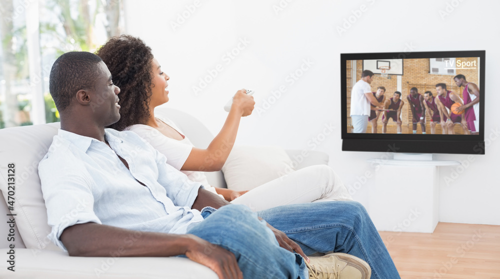 Side view of african american couple sitting at home together watching basketball match on tv