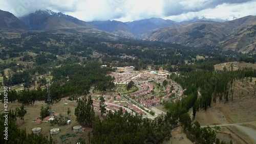 Aerial view from drone panning through a pine forest with a background of mountains, snow-capped mountains and houses and condominiums in El Pinar, Huaras photo