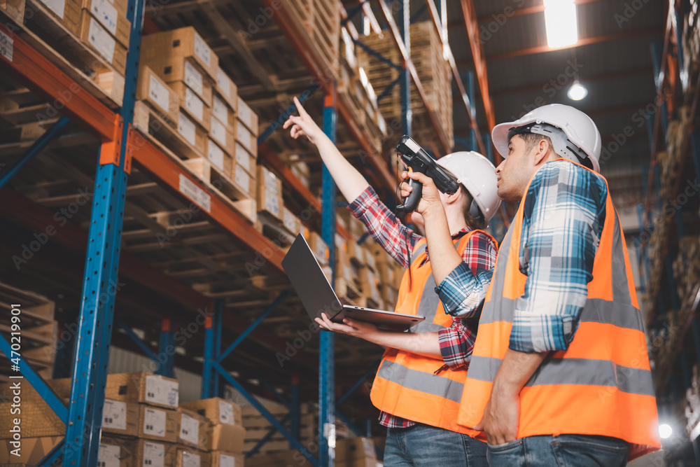 Two logistic staff in safety suite working at warehouse Two logistic staff in safety suite working at warehouse