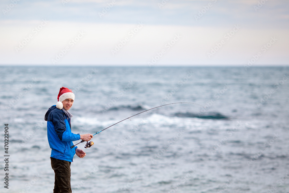 The guy is fishing on the seashore, he holds a spinning rod in his hands The guy is fishing on the seashore, he holds a spinning rod in his hands