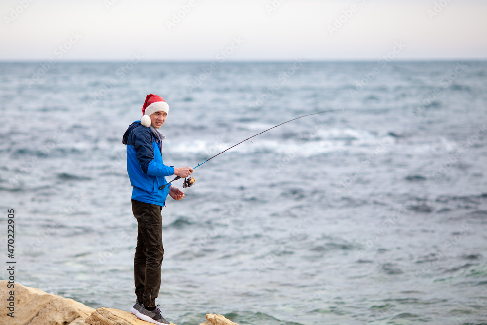 The guy is fishing on the seashore, he holds a spinning rod in his hands The guy is fishing on the seashore, he holds a spinning rod in his hands