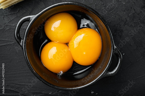 Bright yellow egg yolks, on black stone background, top view flat lay photo