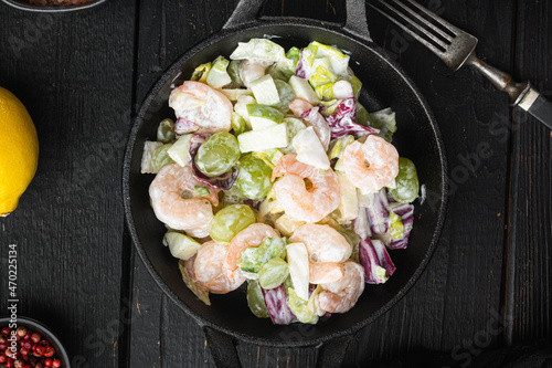 Traditional Waldorf salad with celery, shrimps , with sauce apple and grape, on black wooden table , top view flat lay