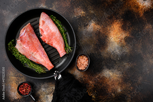 Fish raw snapper, in frying cast iron pan, on old dark rustic table background, top view flat lay, with copy space for text