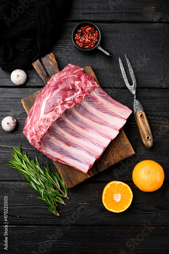 Fresh rack of lamb ribs, on black wooden table background, top view flat lay, with copy space for text