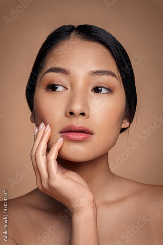 Vertical portrait of beautiful asian woman touching clean glowing hydrated skin