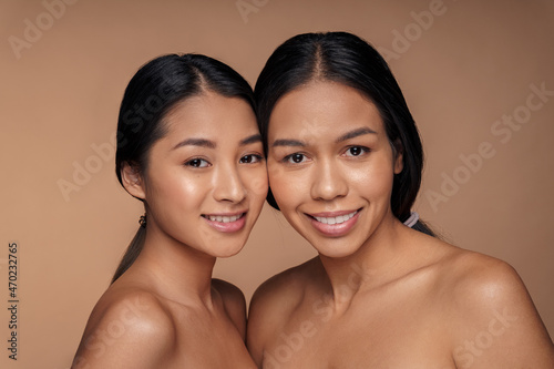 Smiling african american and asian woman with shiny glowing perfect facial skin