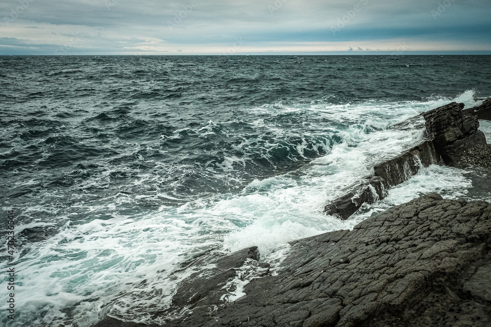 sea waves with splashes and foam wash over the rocky stones