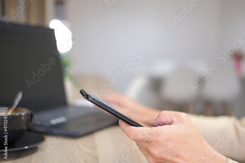 Close-up of a man's hands taken using a smartphone, At the cafe, a man is on his phone, typing messages on social media.