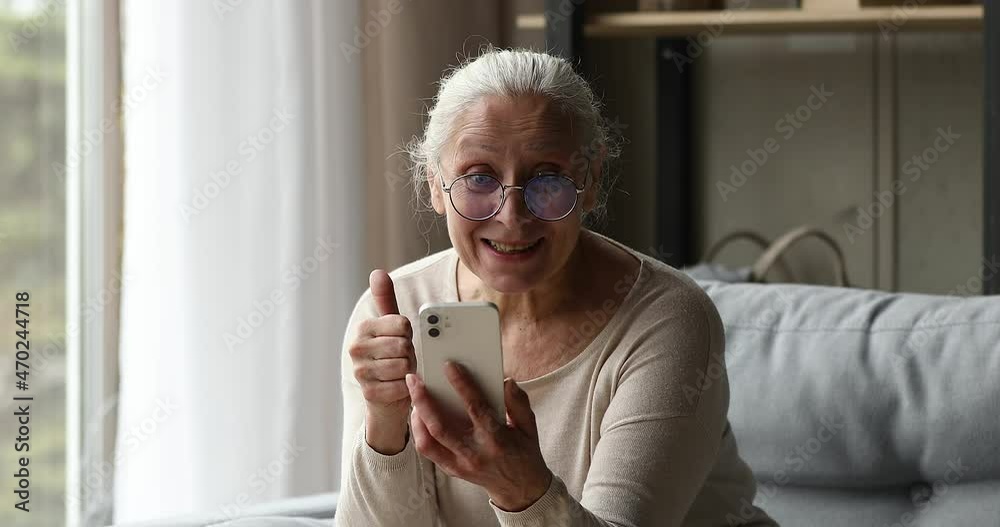 Overjoyed senior adult woman talk to friend relative child by videocall using modern phone smile wave hand share good news looking at screen. Happy older granny enjoy nice virtual conversation on cell Overjoyed senior adult woman talk to friend relative child by videocall using modern phone smile wave hand share good news looking at screen. Happy older granny enjoy nice virtual conversation on cell
