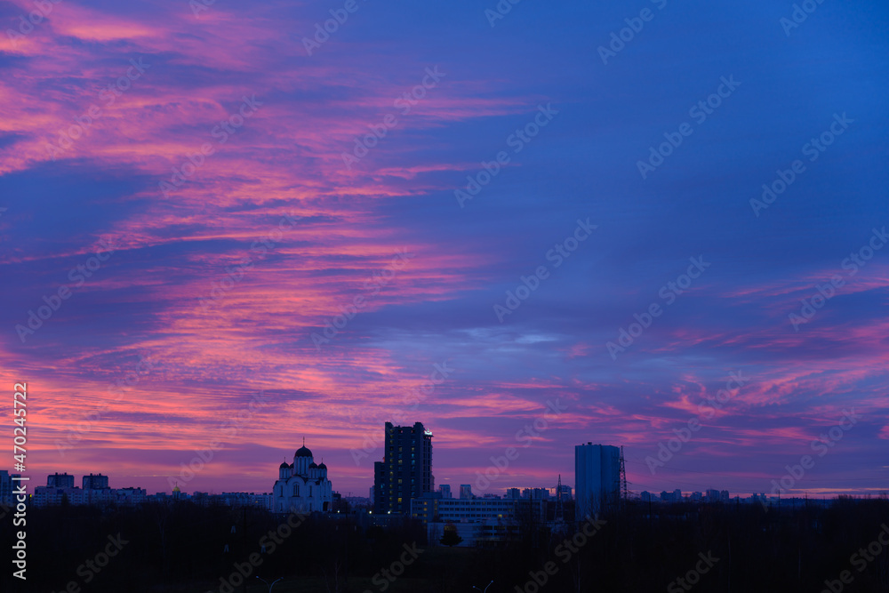 Photo of dark sky with blue red color clouds on city silhouette background